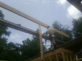 Carpenter setting a ridge beam over a new addition frame — Ice Dam Removal by Roofing Brothers in Calypso
