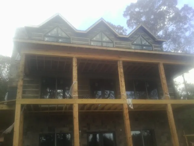 Dormers and porch framing on a large log home under construction — Roof Coating work by our crew in Calypso