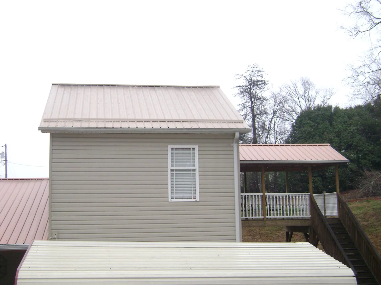 Tan metal roofs on a two story addition and attached porch, from a Roof Replacement job in Calypso
