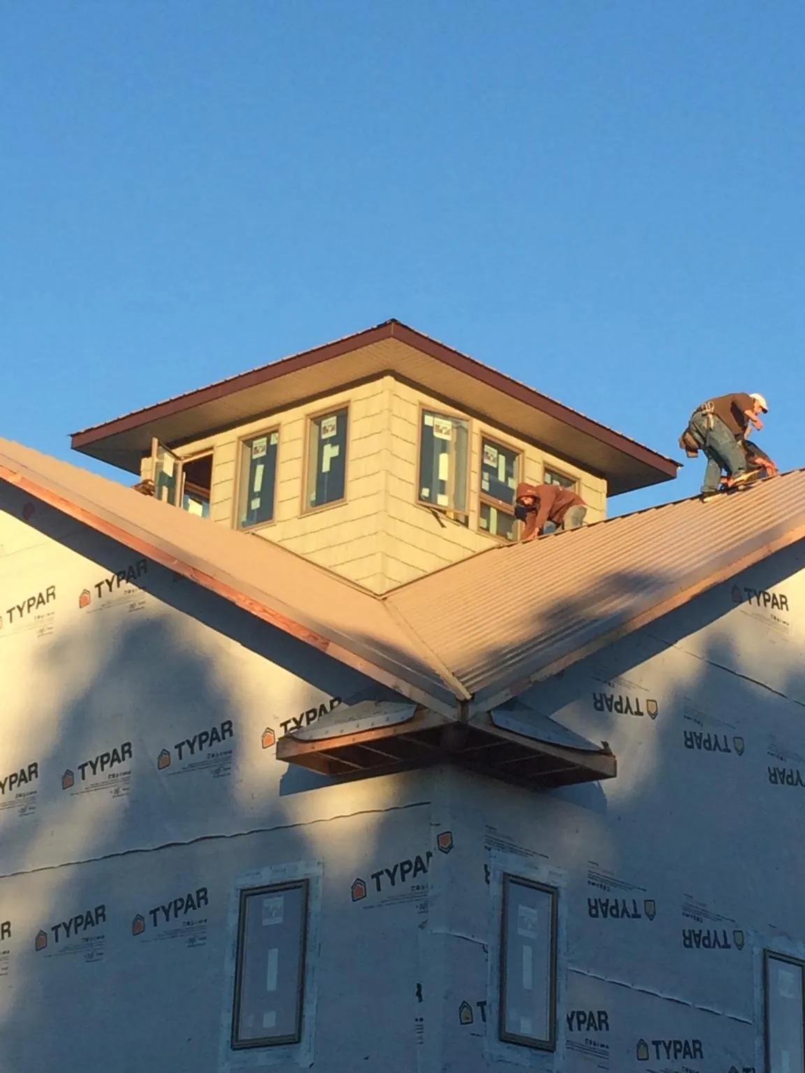Roofers working around a rooftop cupola on a new metal roof at sunset — Roof Waterproofing in Calypso by Roofing Brothers